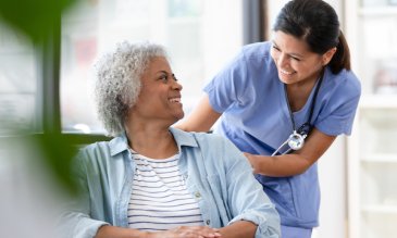 Nurse smiling at patient in a wheelchair