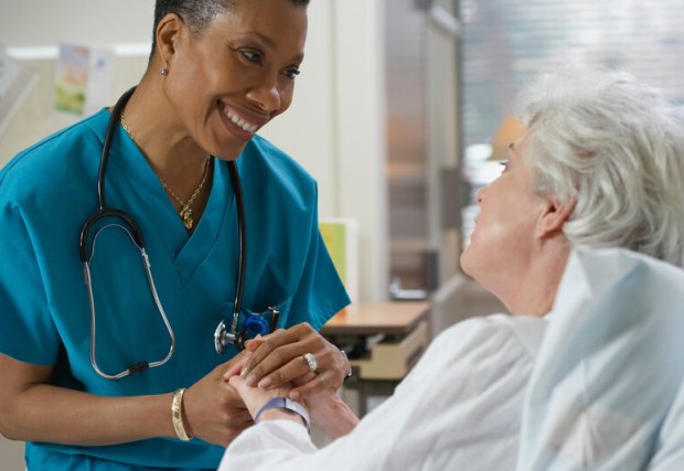 Nurse smiling and holding patient's hand
