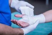 A doctor wrapping a wound on a patient's arm