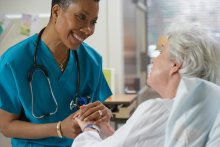 Nurse smiling and holding patient's hand