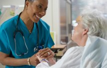 Nurse smiling and holding patient's hand